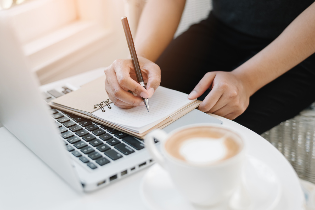 female hands with pen writing on notebook